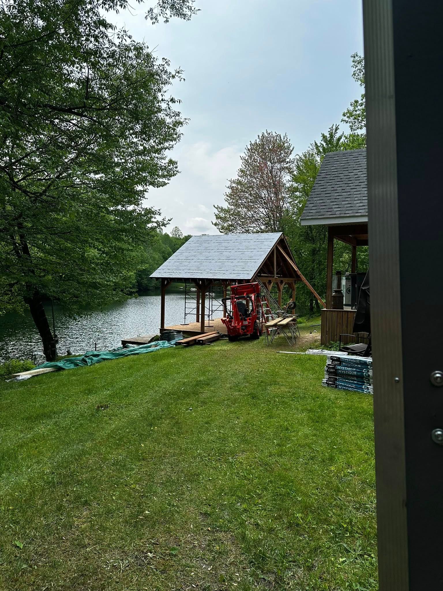 Cour gazonnée au bord du lac avec un petit kiosque rouge et des arbres sous un ciel nuageux