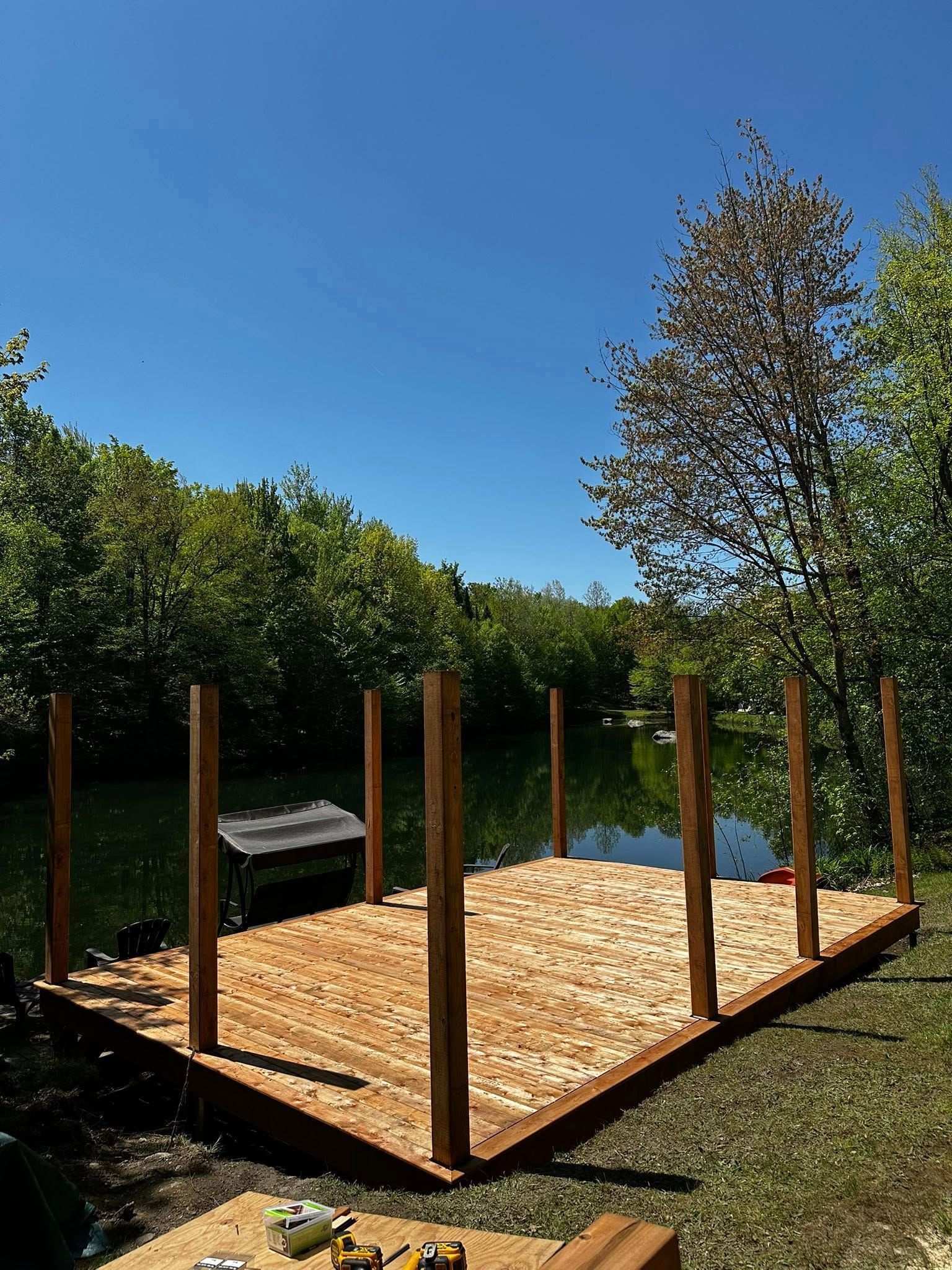 Plateforme de jardin clôturée en bois avec litière de paille fraîche à côté des arbres et du ciel bleu