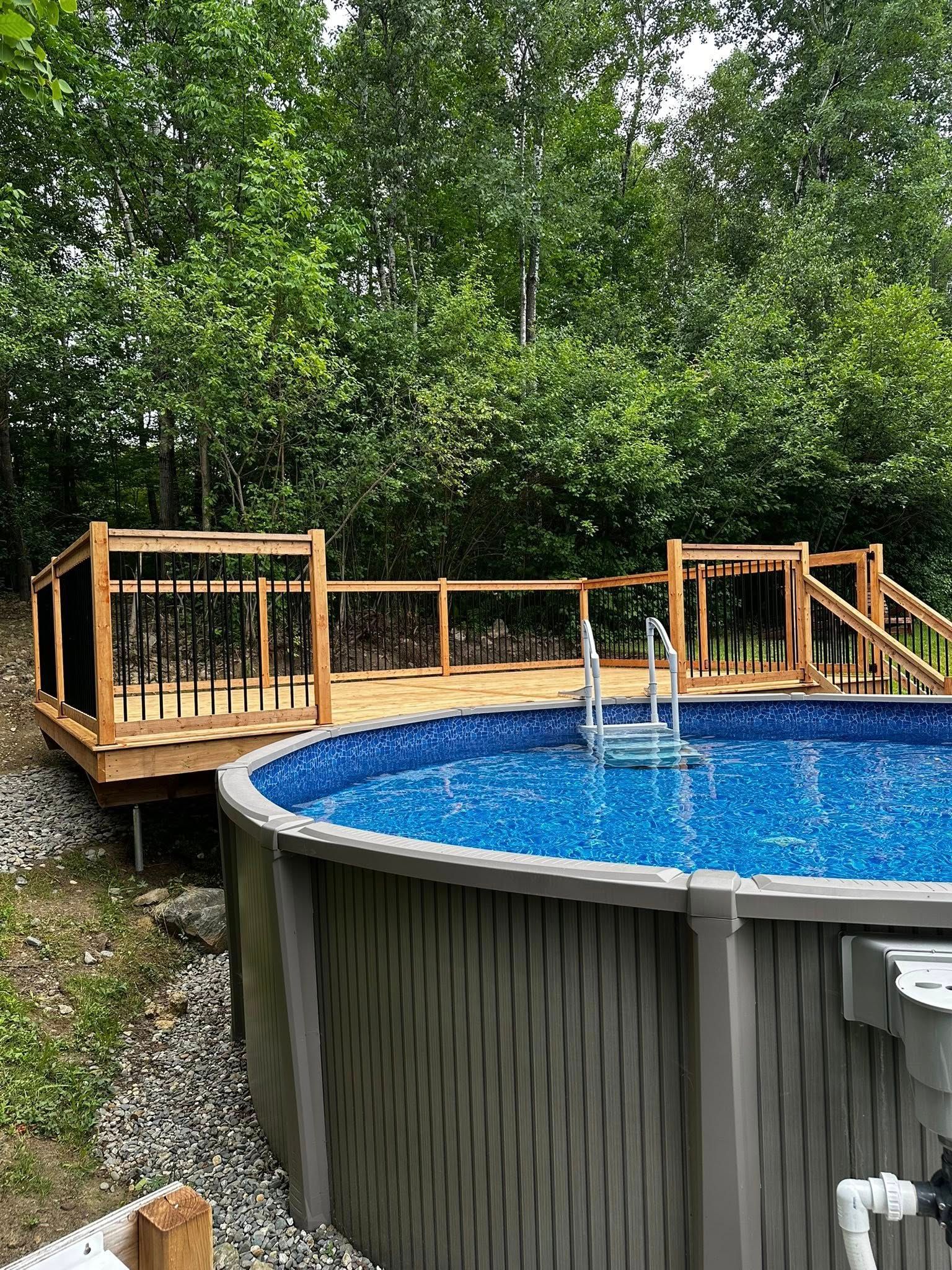 Piscine hors sol avec terrasse en bois et échelle, entourée d'arbres et d'une cour en gravier