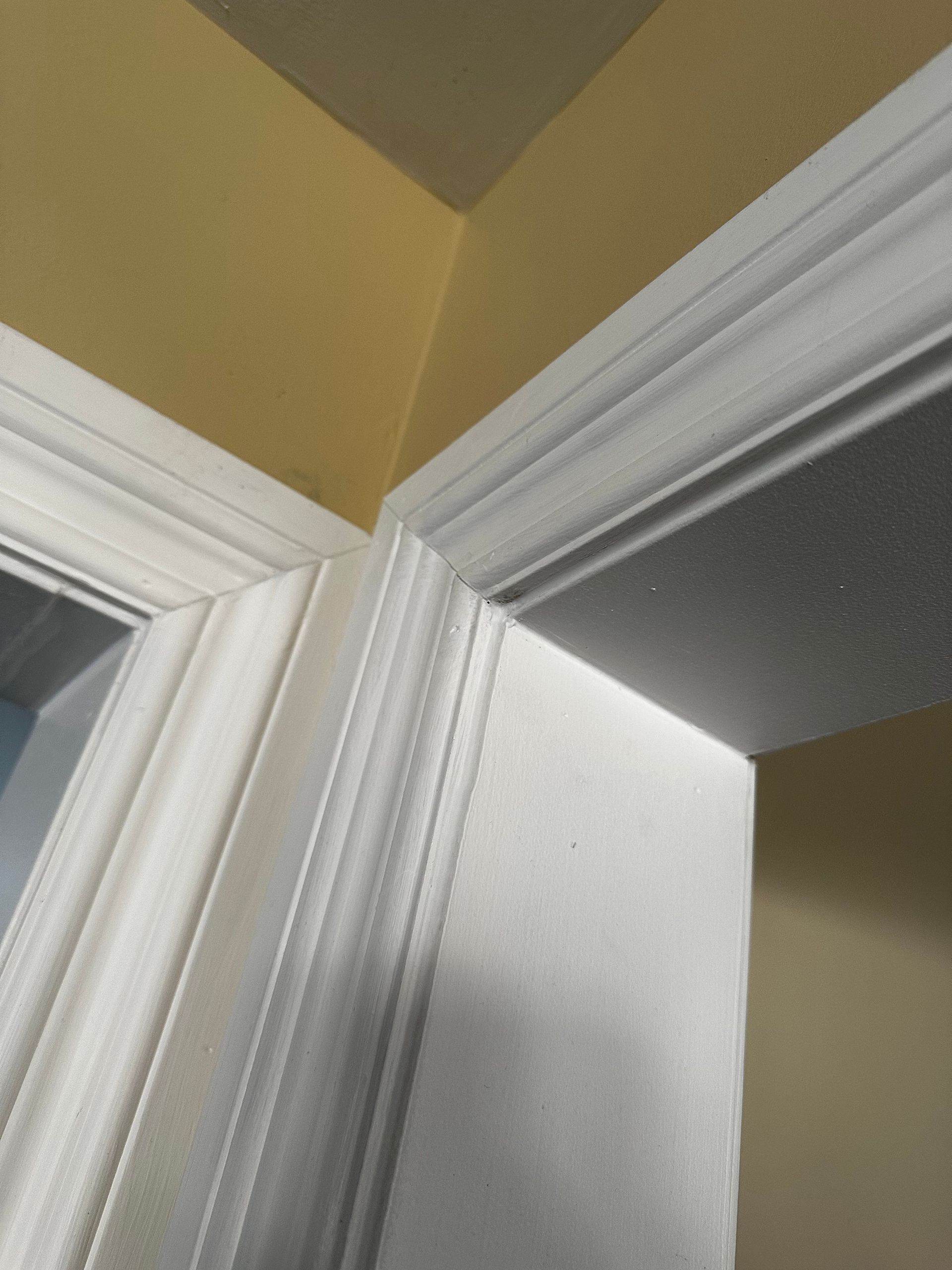 Des cadres de porte blancs se rejoignent dans un angle de plafond beige, dans un couloir intérieur.