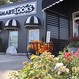 Smartlooks storefront with black and white awnings. A wagon filled with pumpkins and flowers in front.