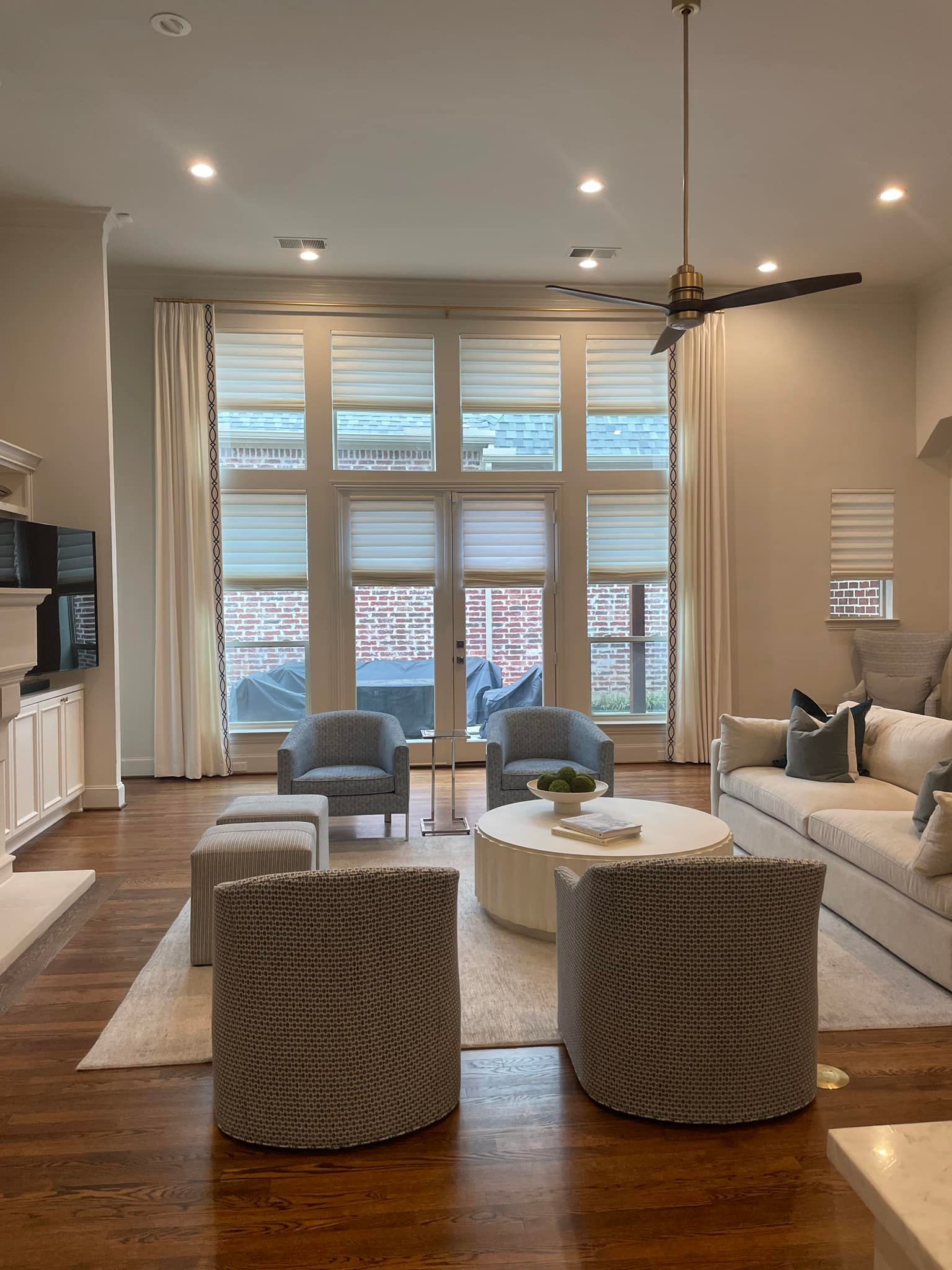 Living room with large windows, light furniture, and a rug.