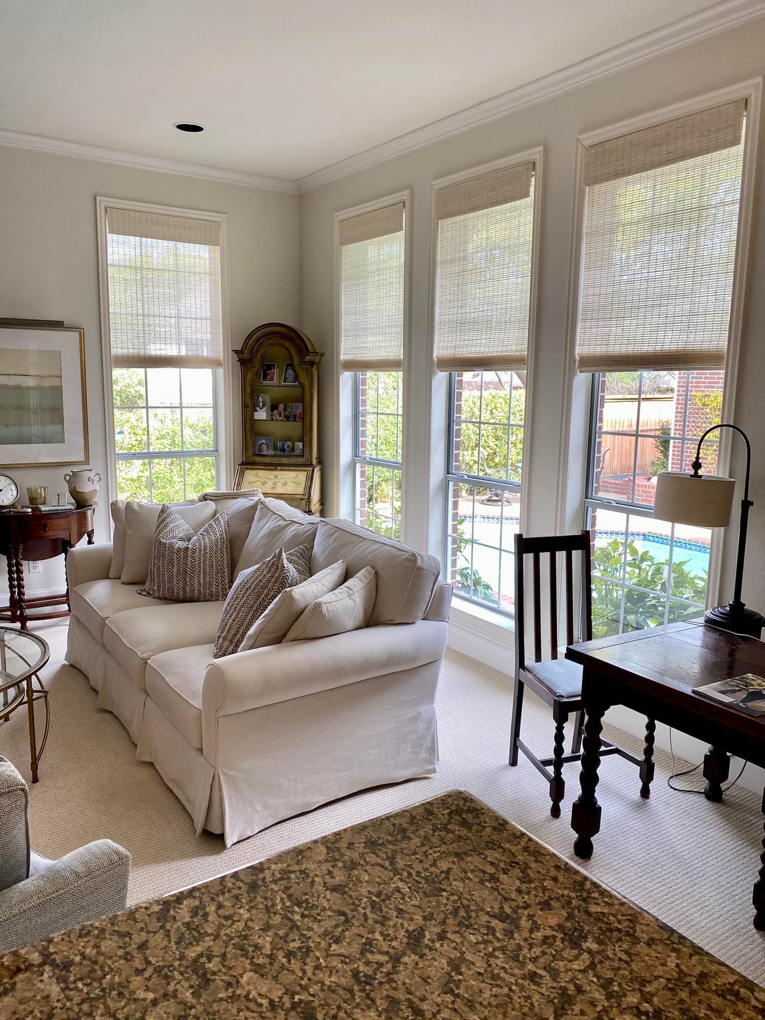 Living room with white sofa, three windows, desk, and area rug.