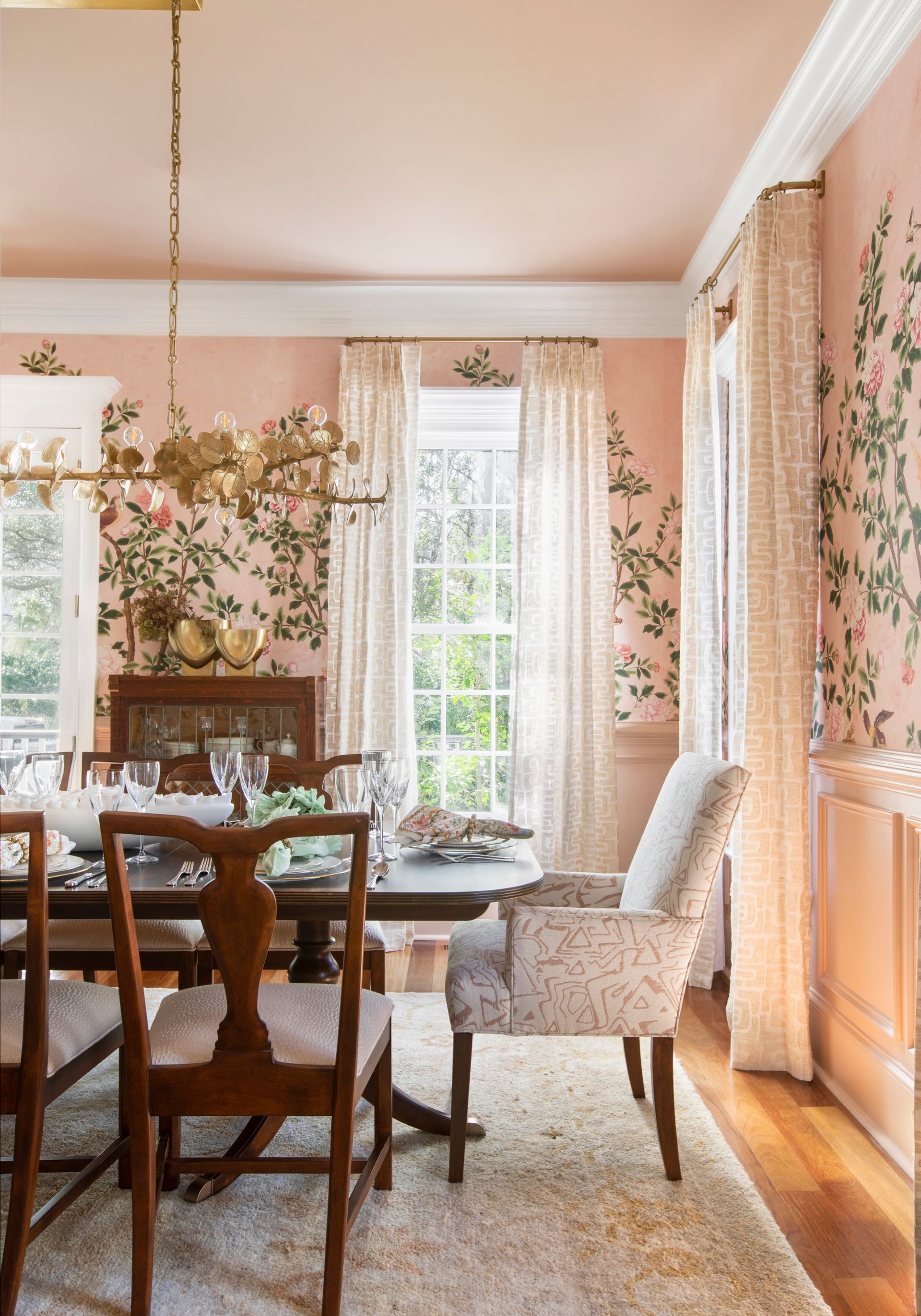 Elegant dining room with floral wallpaper, wooden table, and patterned curtains.