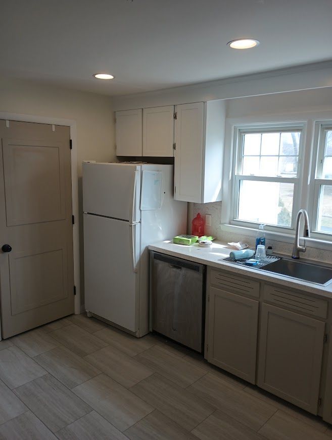 Kitchen with white cabinets, refrigerator, and a stainless steel dishwasher and sink.