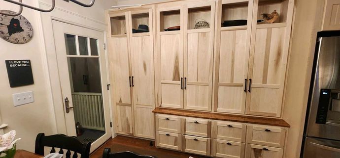 Light wood cabinets with drawers and display shelves. A side door and a refrigerator are nearby.