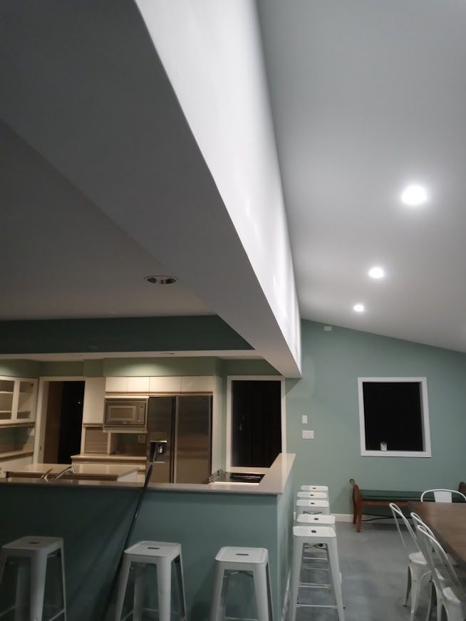 Open-plan kitchen and dining area with a teal-painted wall and white accents. Bar stools line a counter.