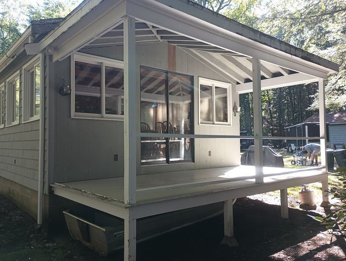 Grey house with a porch. White trim, windows, and railing. Sunny day.