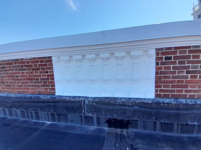 Brick building facade with white trim, a decorative molding, and a dark roof.