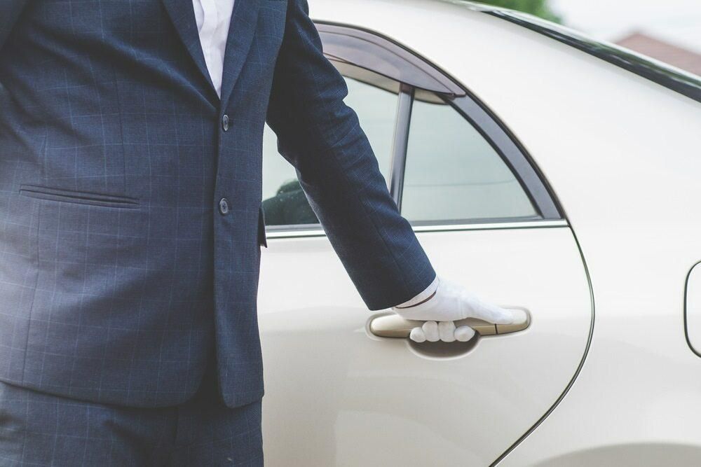 A Man in A Suit Is Opening the Door of A White Car — Greenaway's Taxi in Taree, NSW