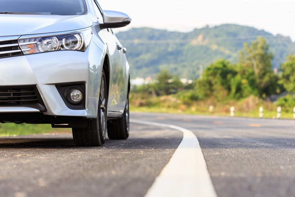 A Silver Car Is Driving Down a Curvy Road — Greenaway's Taxi in Diamond Beach, NSW