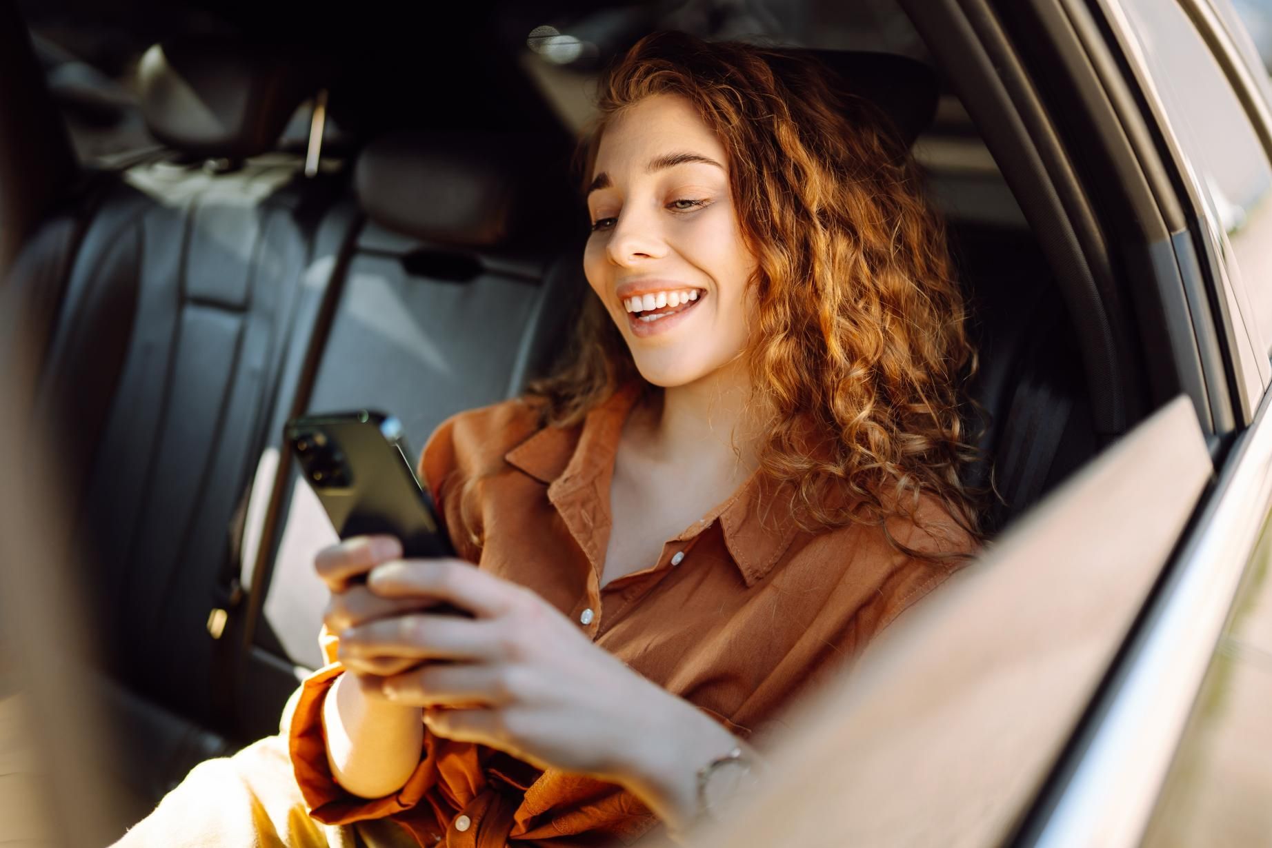 A Woman Is Sitting in The Back Seat of A Car Looking at Her Cell Phone — Greenaway's Taxi in Tinonee, NSW