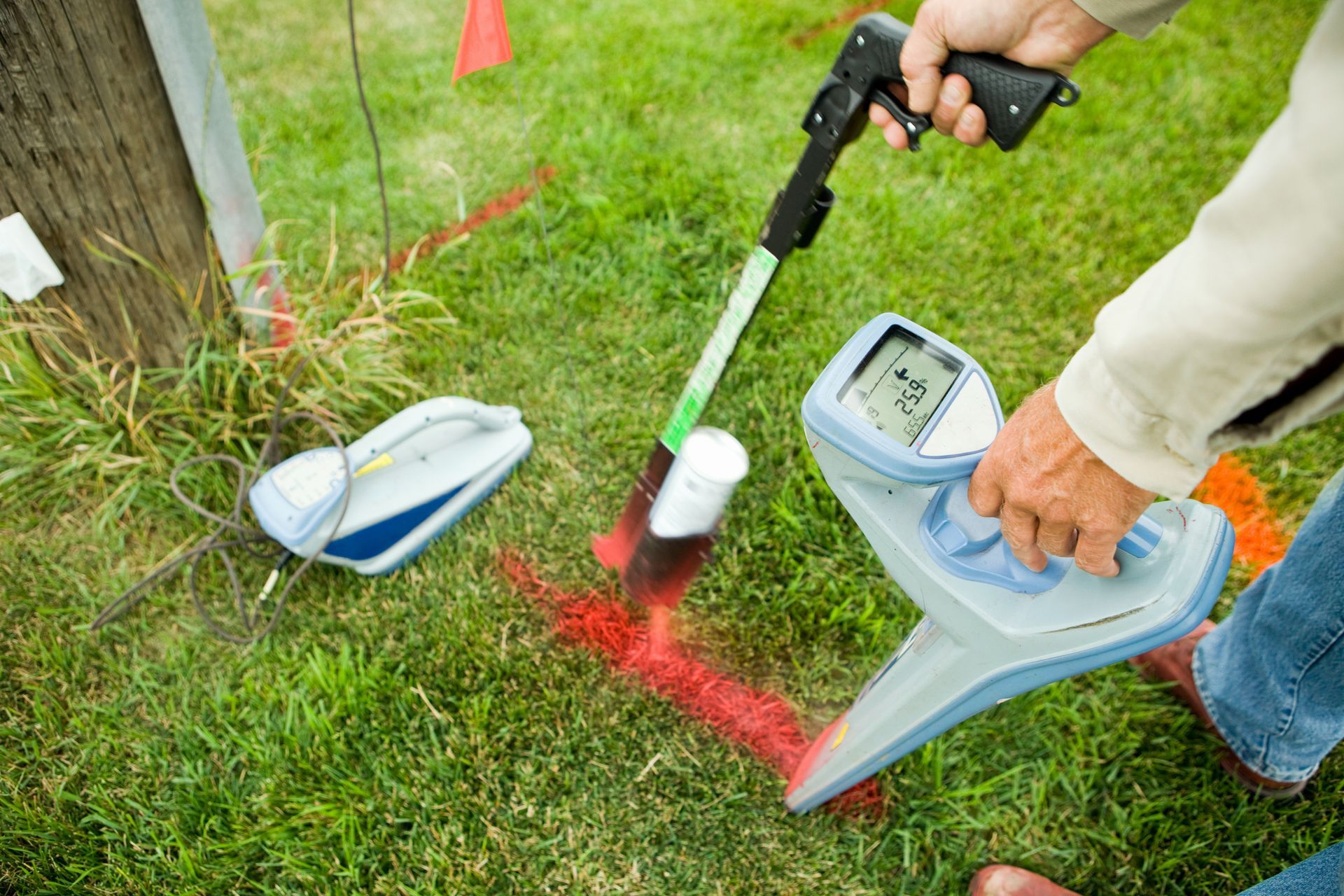 A person is using a metal detector in the grass.