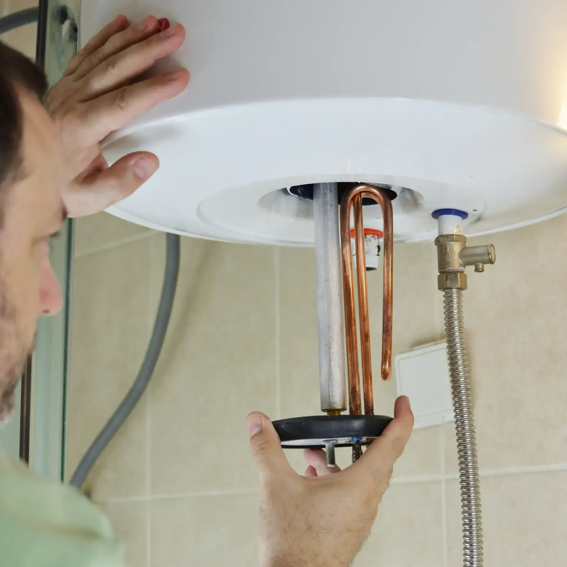 Aarden Air Service Heating & Air Conditioning- A man is fixing a water heater in a bathroom