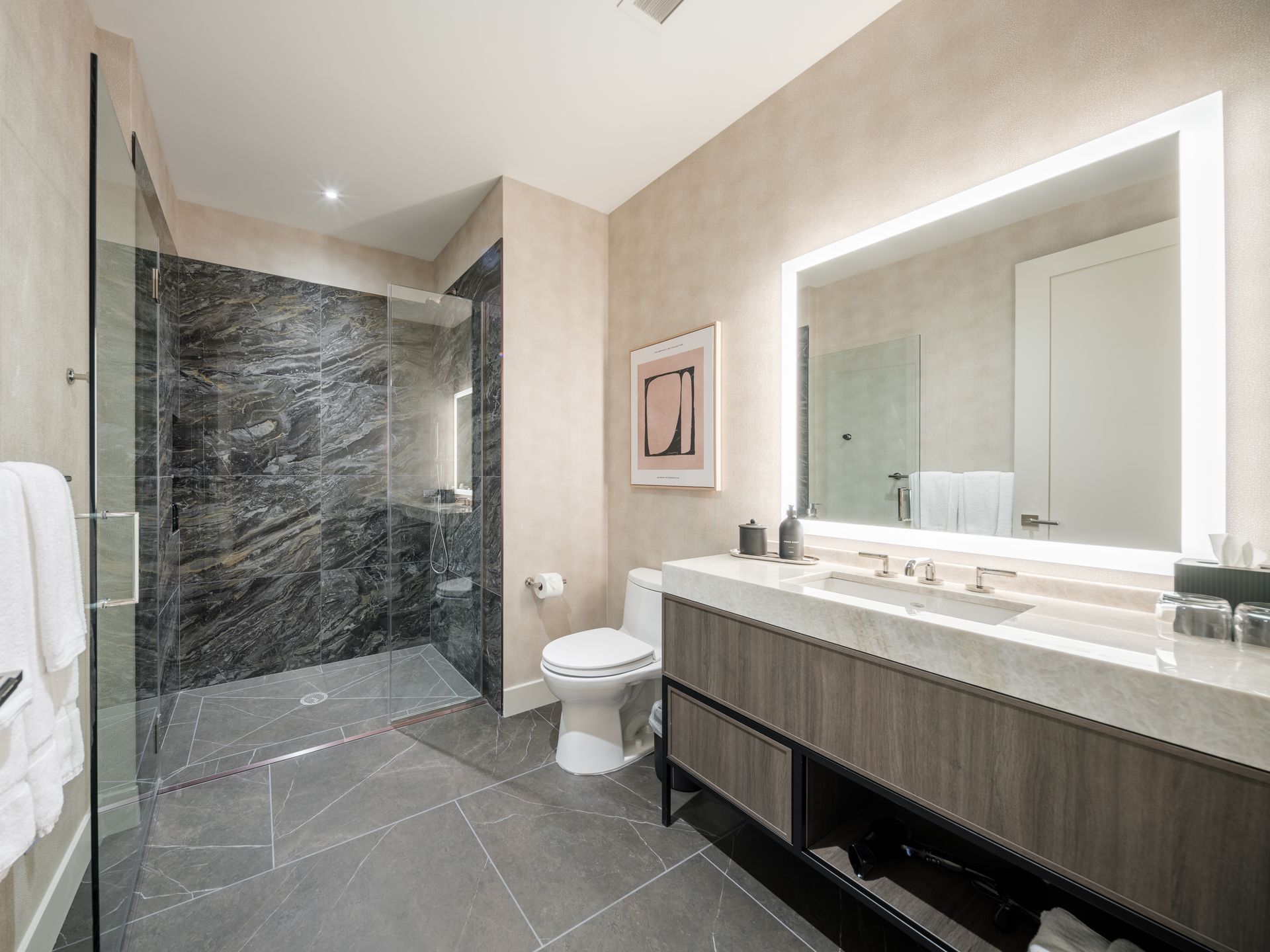 A bathroom with a toilet , sink , mirror and walk in shower.