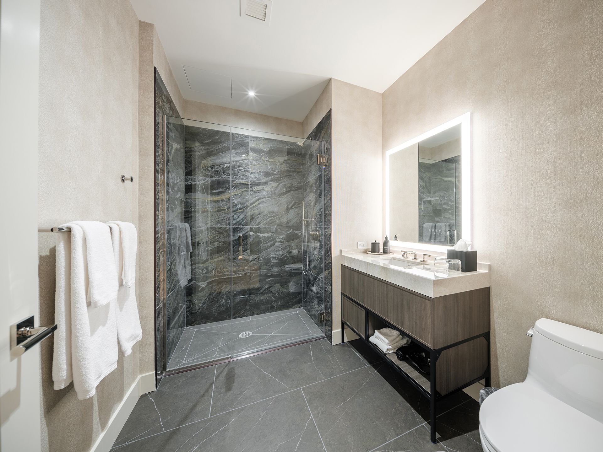 A bathroom with a toilet , sink , mirror and walk in shower.
