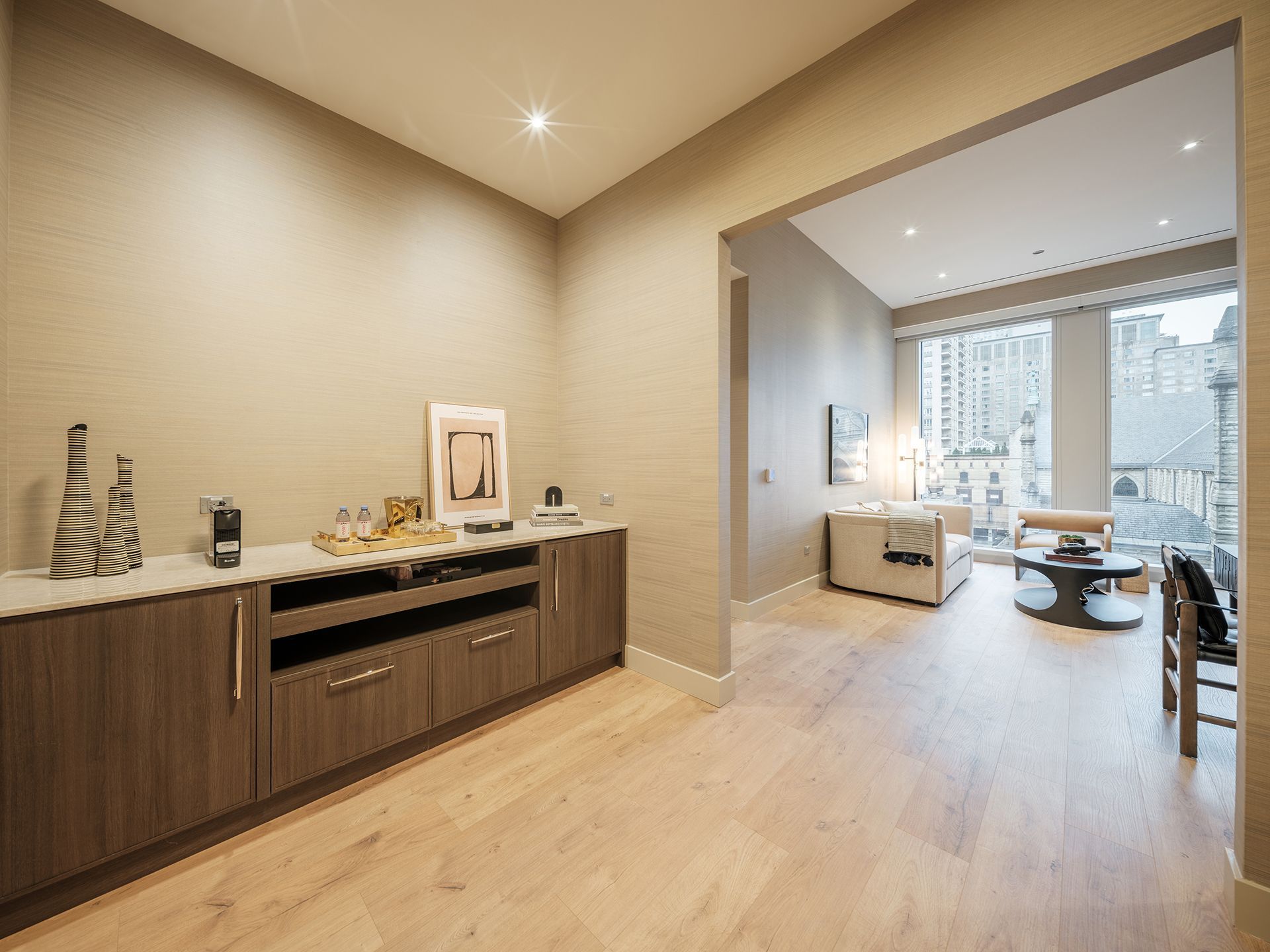 A living room with hardwood floors and a bar in the middle of the room.