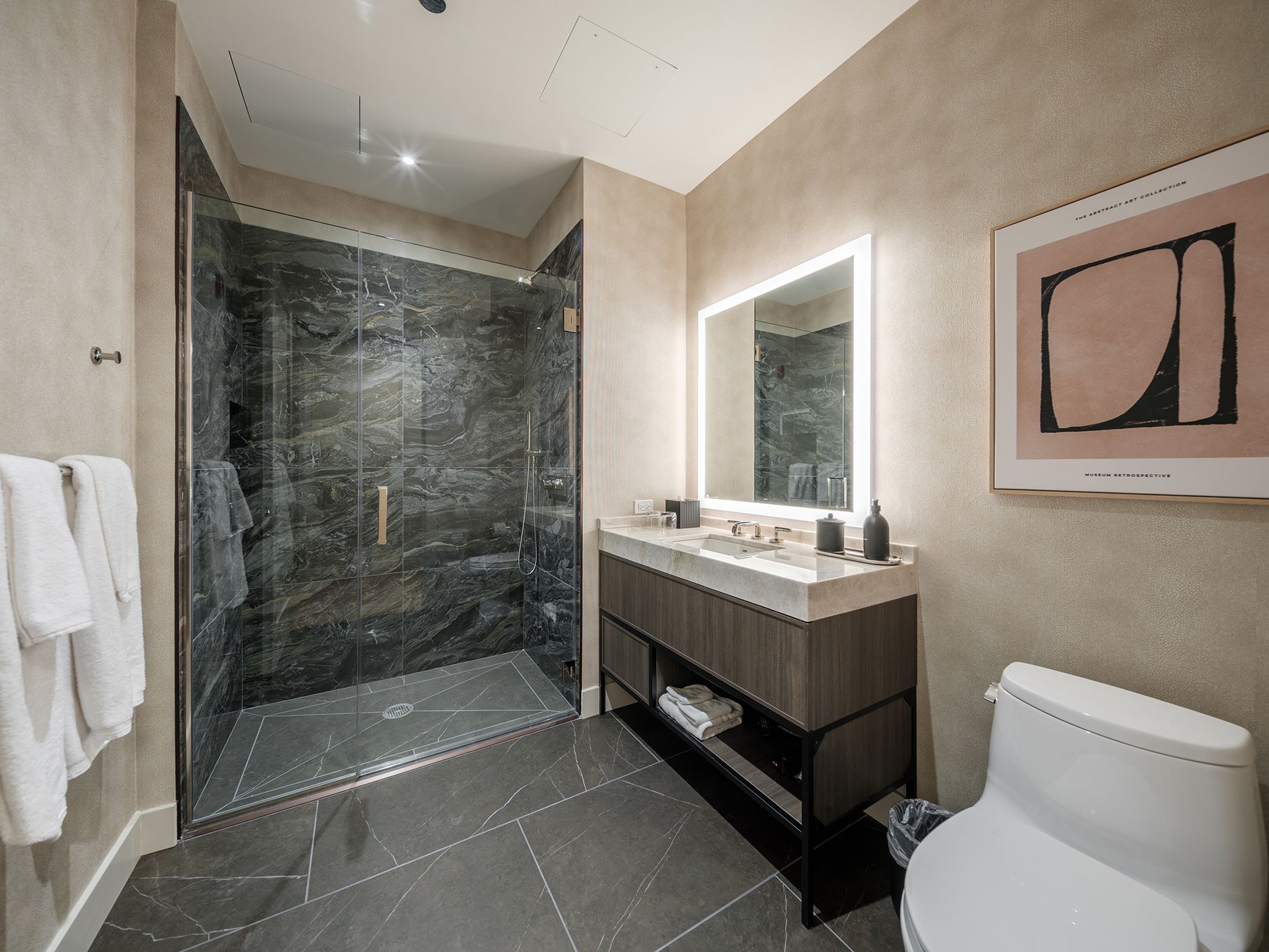 A bathroom with a toilet , sink , mirror and walk in shower.