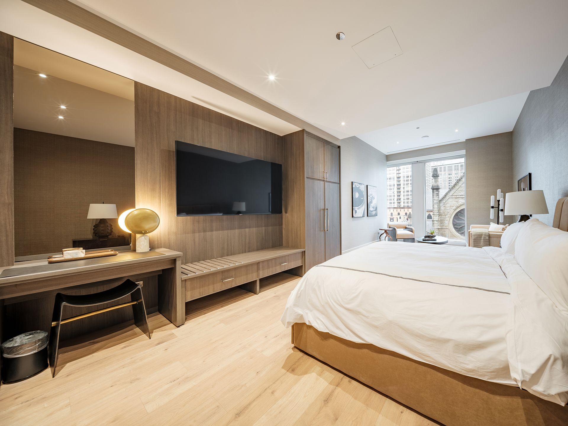 A hotel room with a bed , desk , television and mirror.