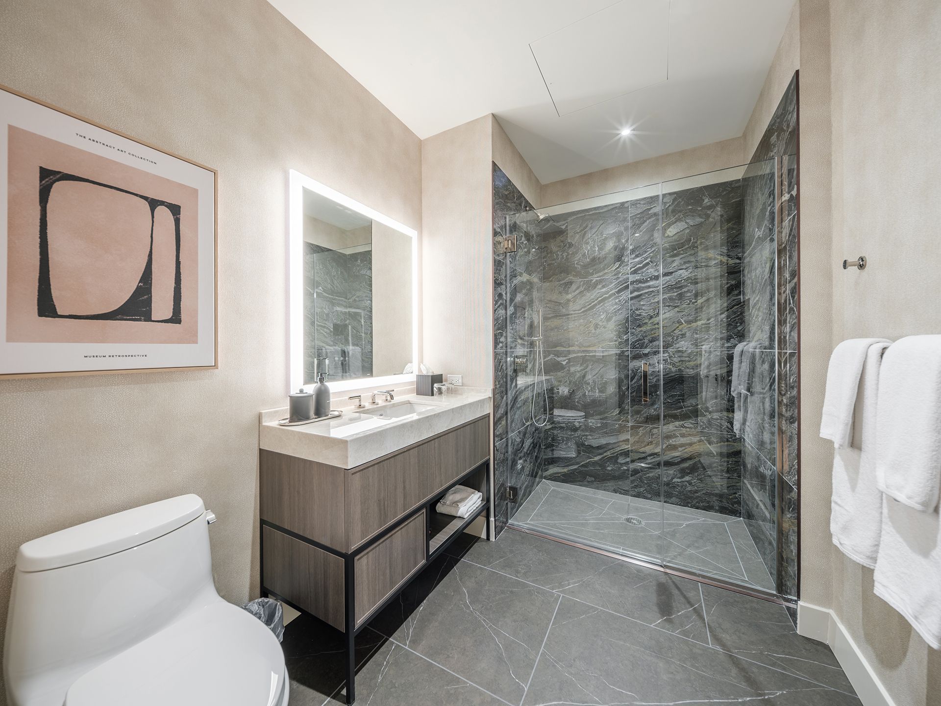 A bathroom with a toilet , sink , mirror and walk in shower.