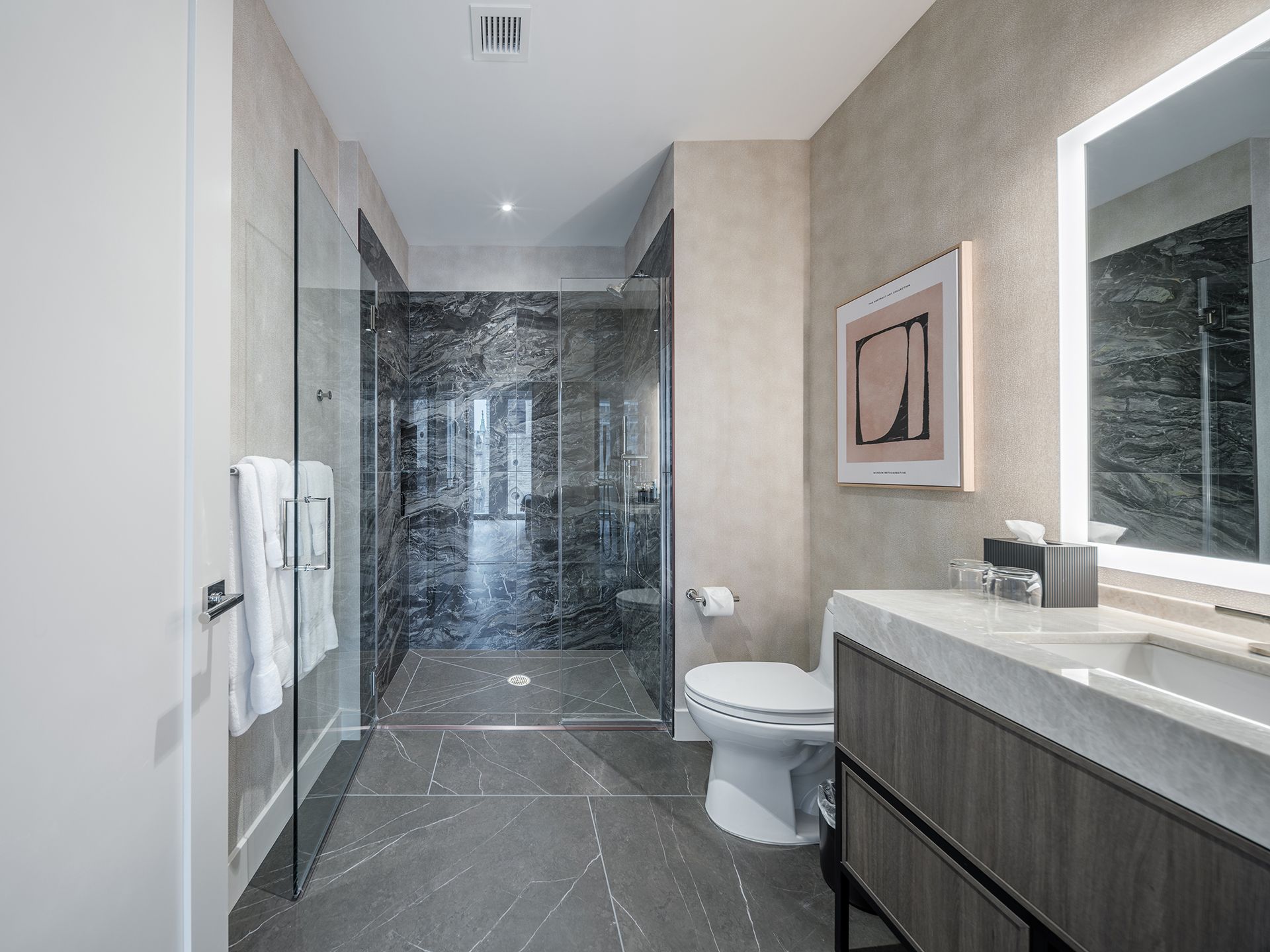 A bathroom with a toilet , sink and walk in shower.