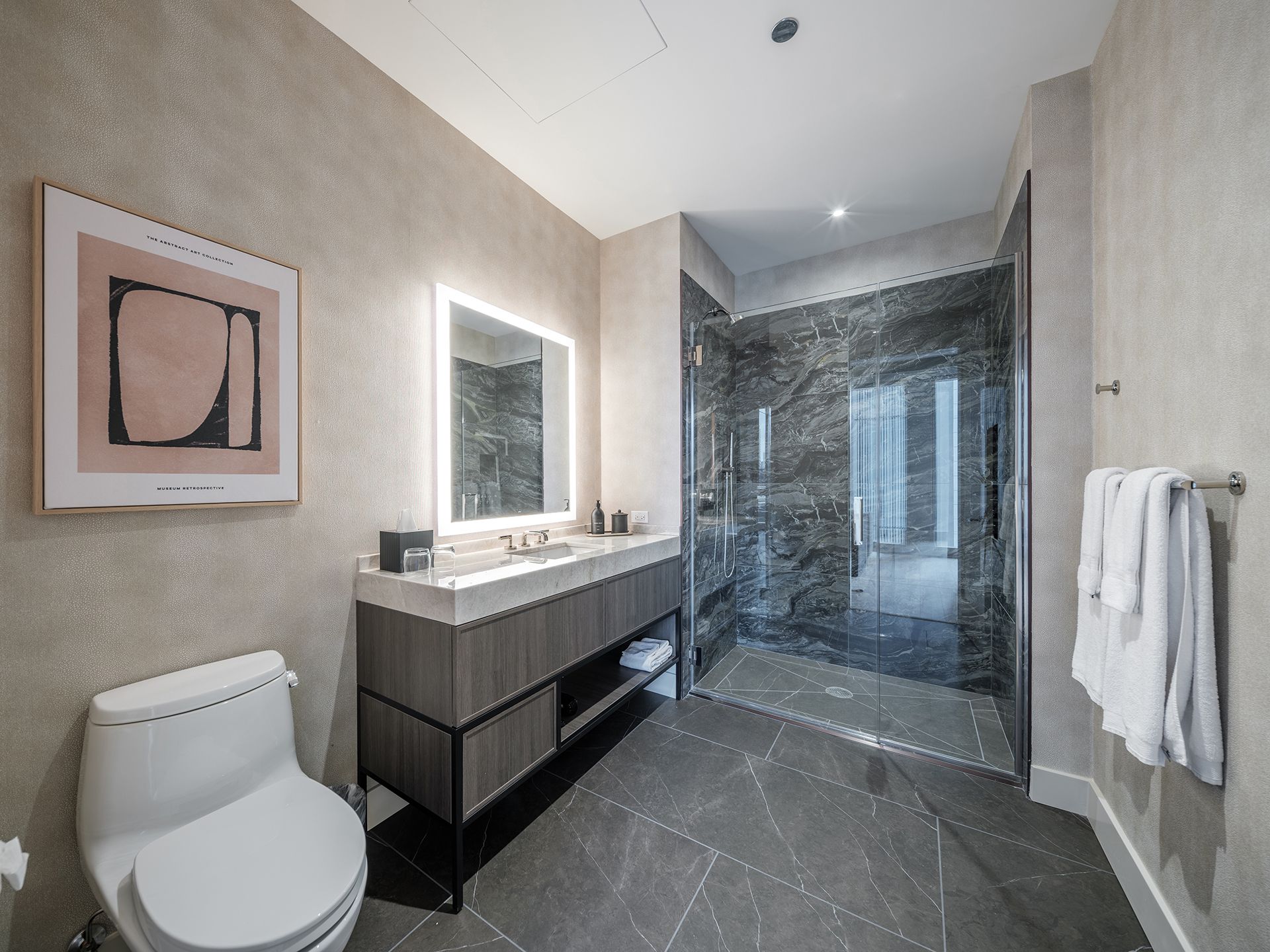 A bathroom with a toilet , sink , mirror and walk in shower.