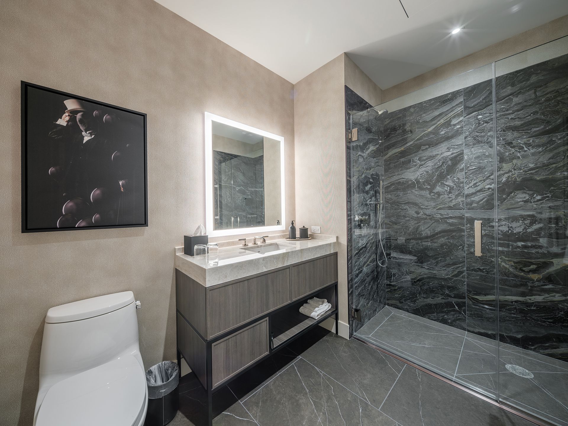 A bathroom with a toilet , sink , mirror and walk in shower.