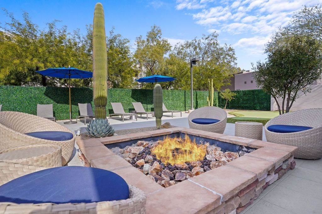Outdoor communal lounge area with a stone fire pit, cactus plants, and blue-cushioned seating at Legacy Apartments at Dove Mountain in Marana, AZ.