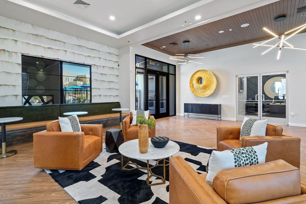 Interior lounge in a residential lobby with tan leather seating and a round coffee table at Legacy Apartments at Dove Mountain in Marana, AZ.