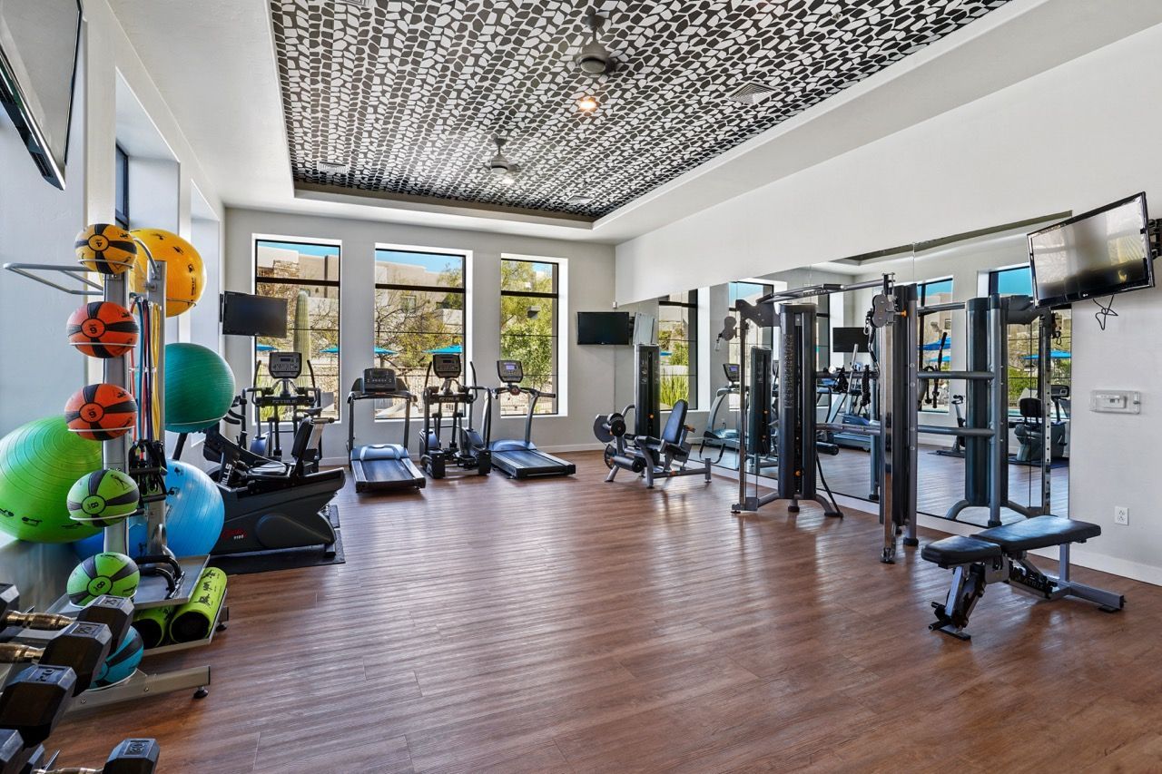 Modern fitness center with cardio equipment, free weights, and mirrors at Legacy Apartments at Dove Mountain in Marana, AZ.