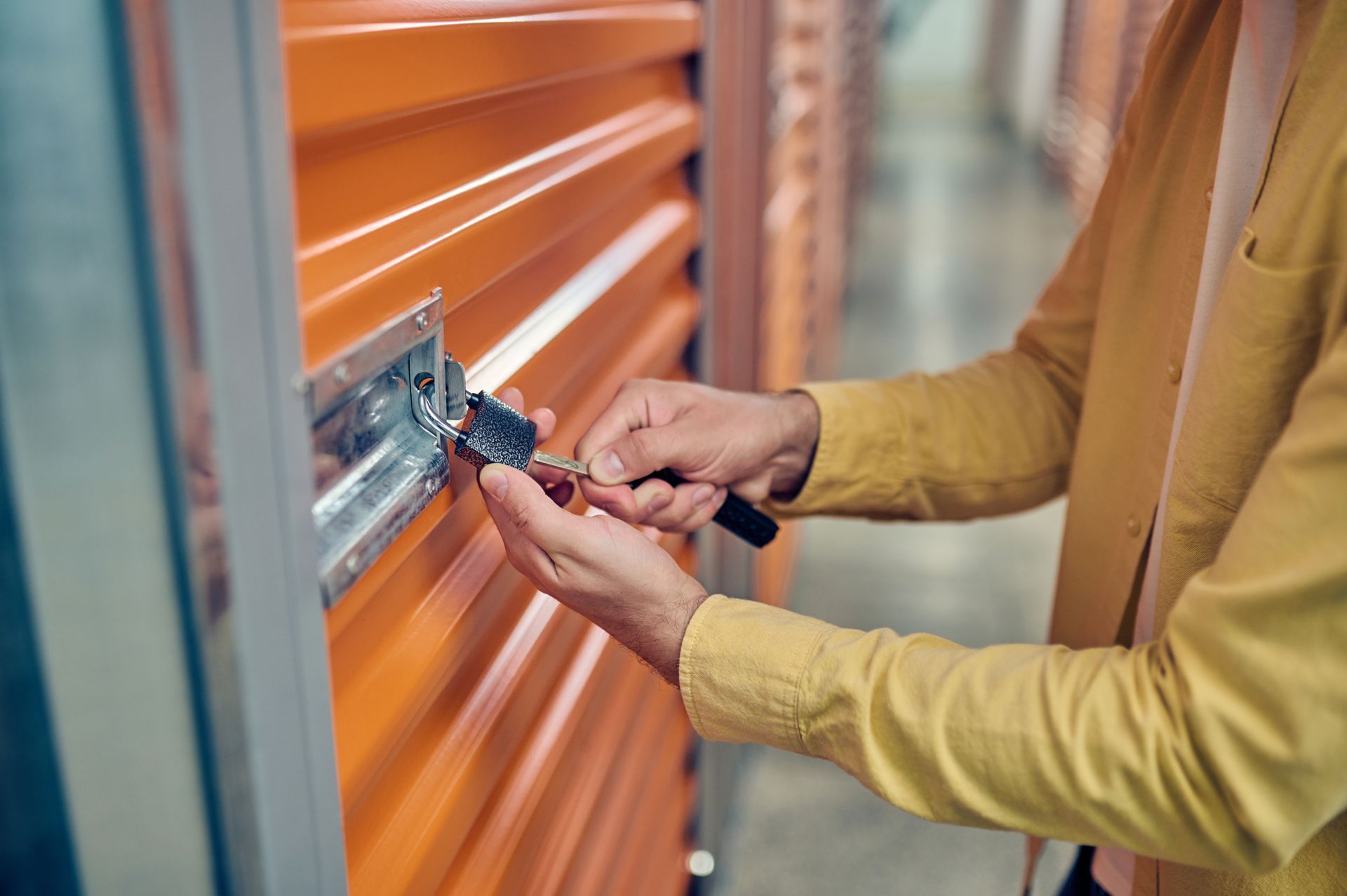 A person is opening the lock of a storage unit.