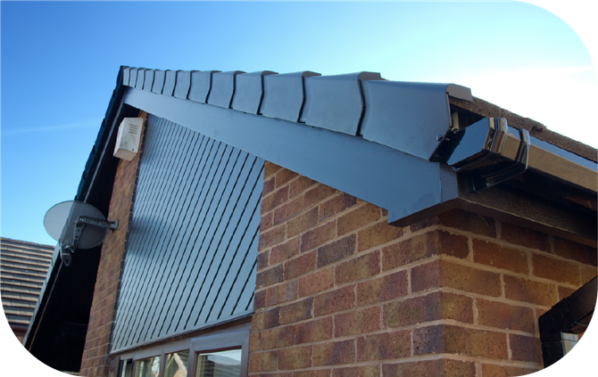 Close-up of a brick house corner featuring dark roof tiles, a black fascia board, and a patterned louvered wall panel.