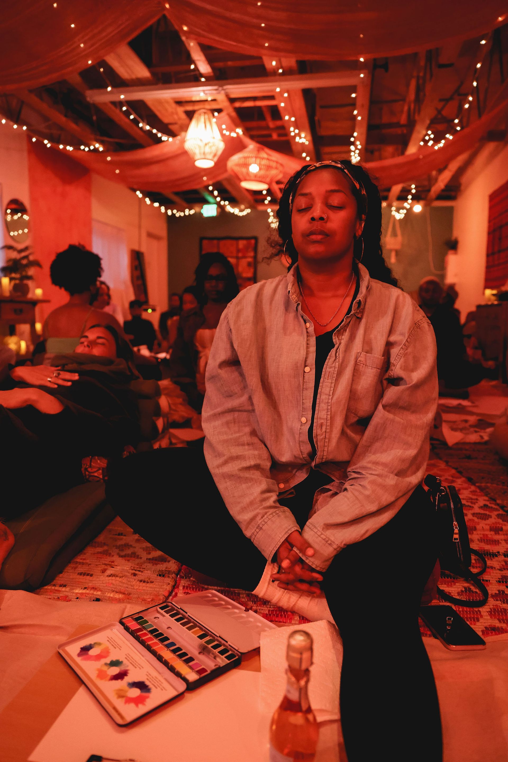 A woman is sitting on the floor in a room with her eyes closed.