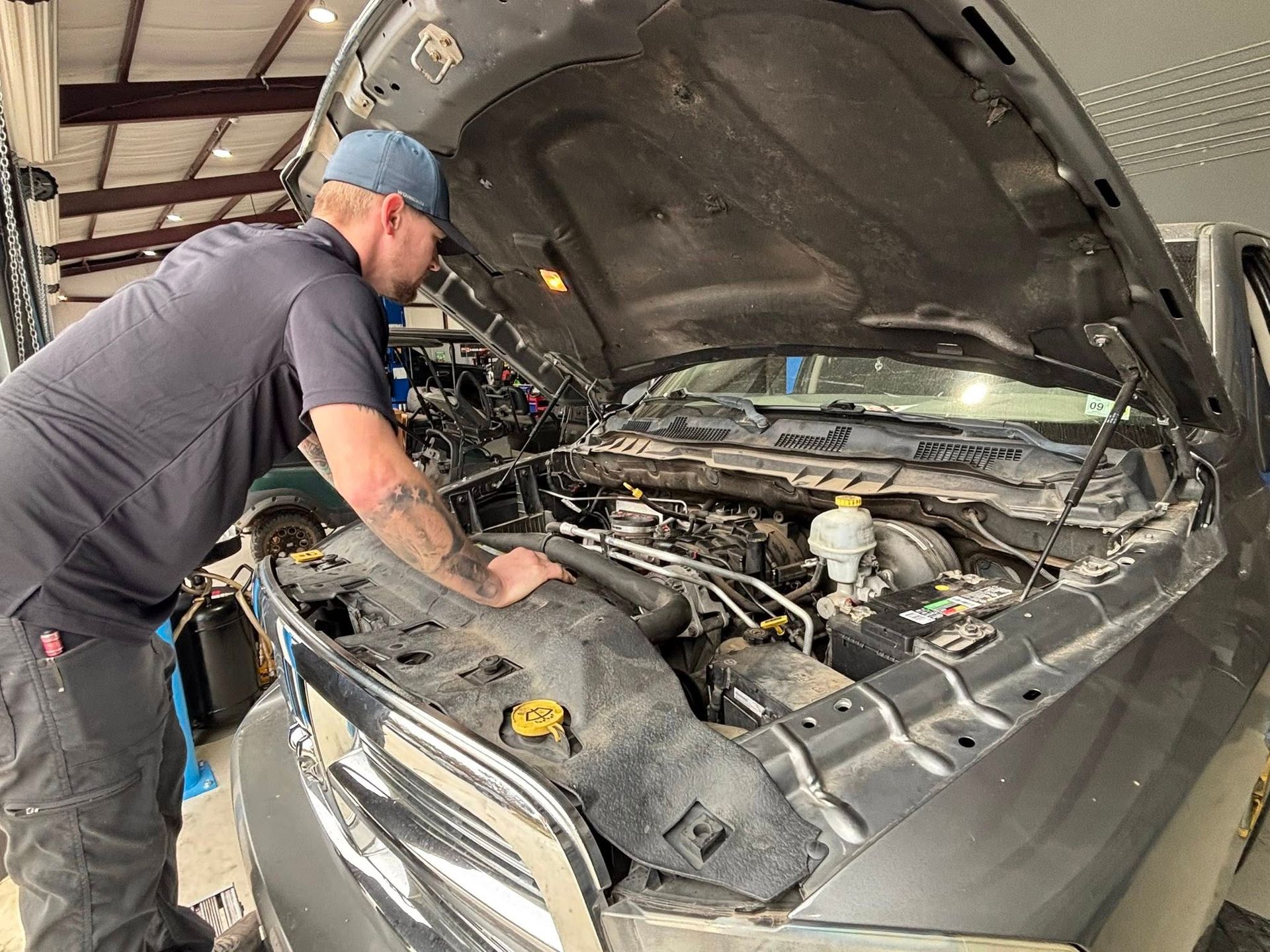 Mechanic inspecting an SUV engine bay with the hood open in a garage