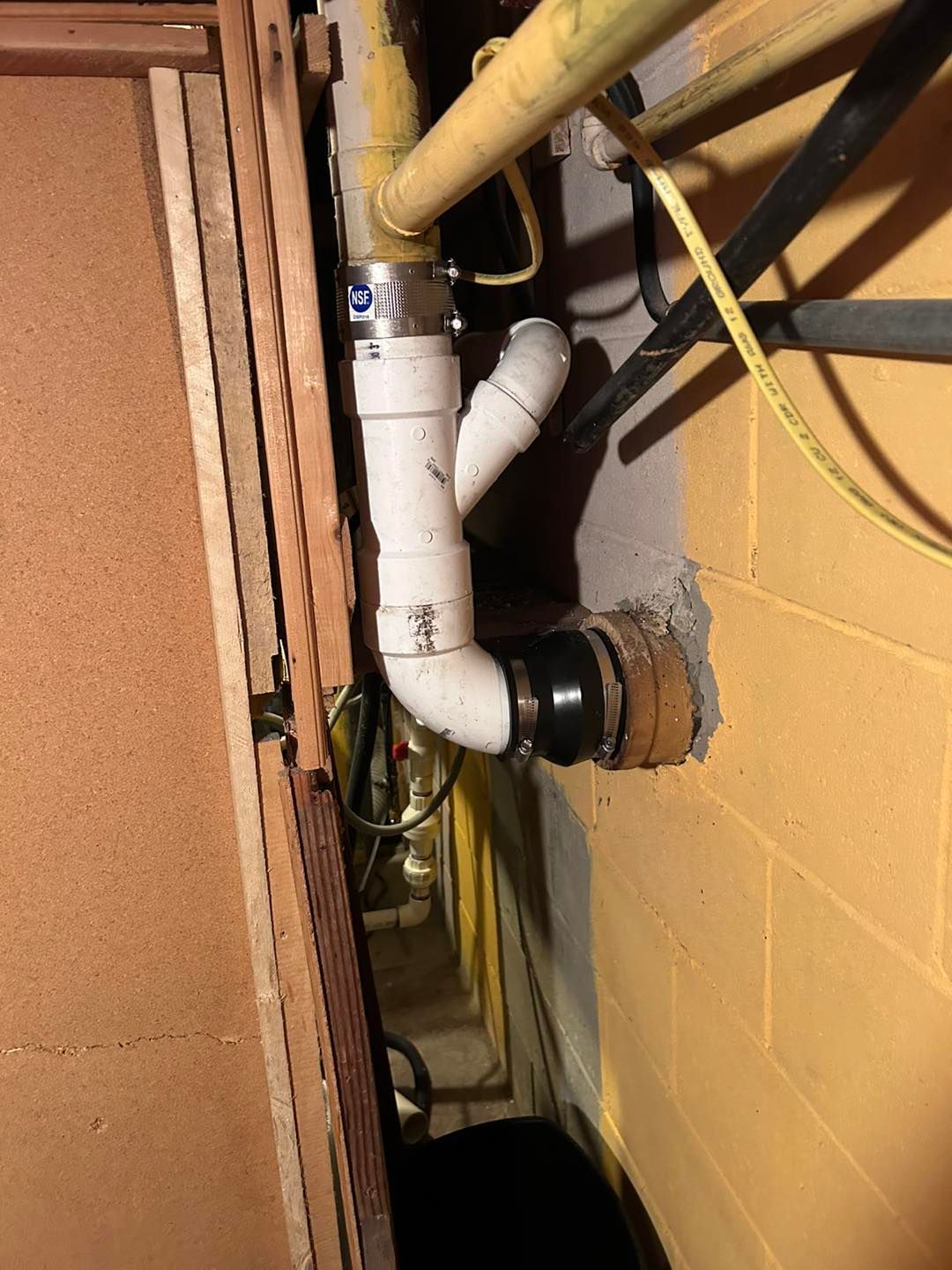 A bunch of pipes are connected to a wall in a basement.