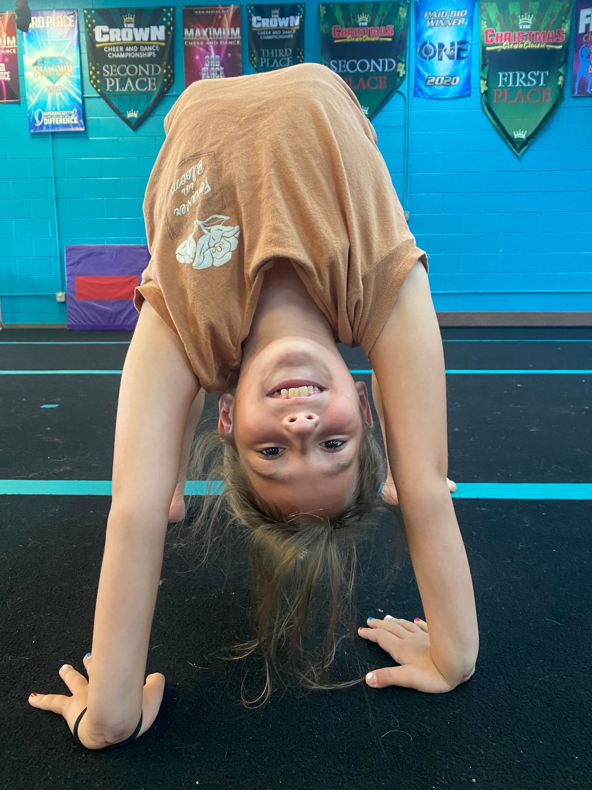 A person performing a bridge pose on a gym mat in front of colorful banners.