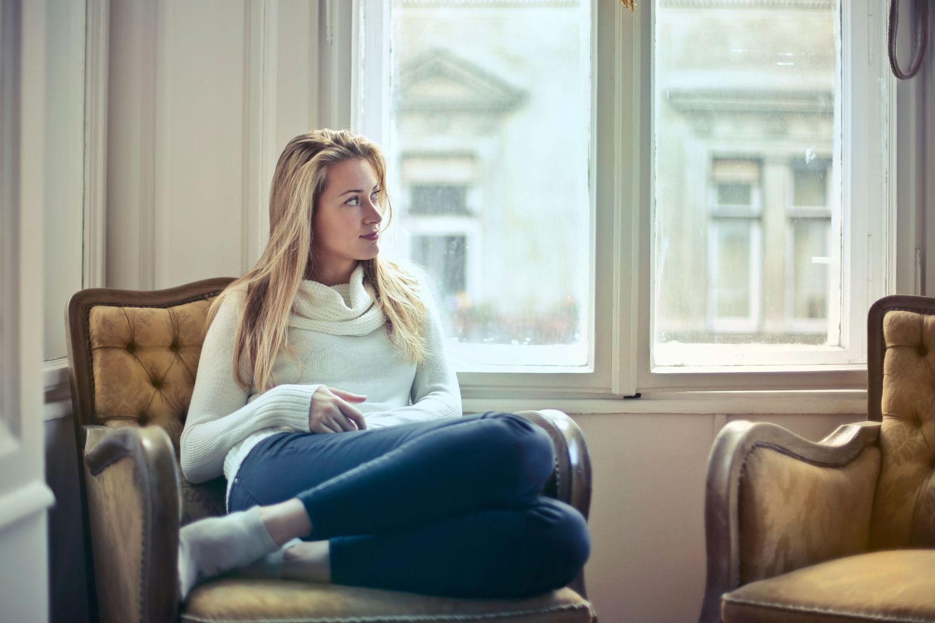 Woman sitting in an armchair, looking thoughtfully into the distance.
