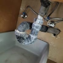 A sink with a faucet and a pipe underneath it.