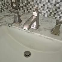 A bathroom sink with a stainless steel faucet and marble counter top.