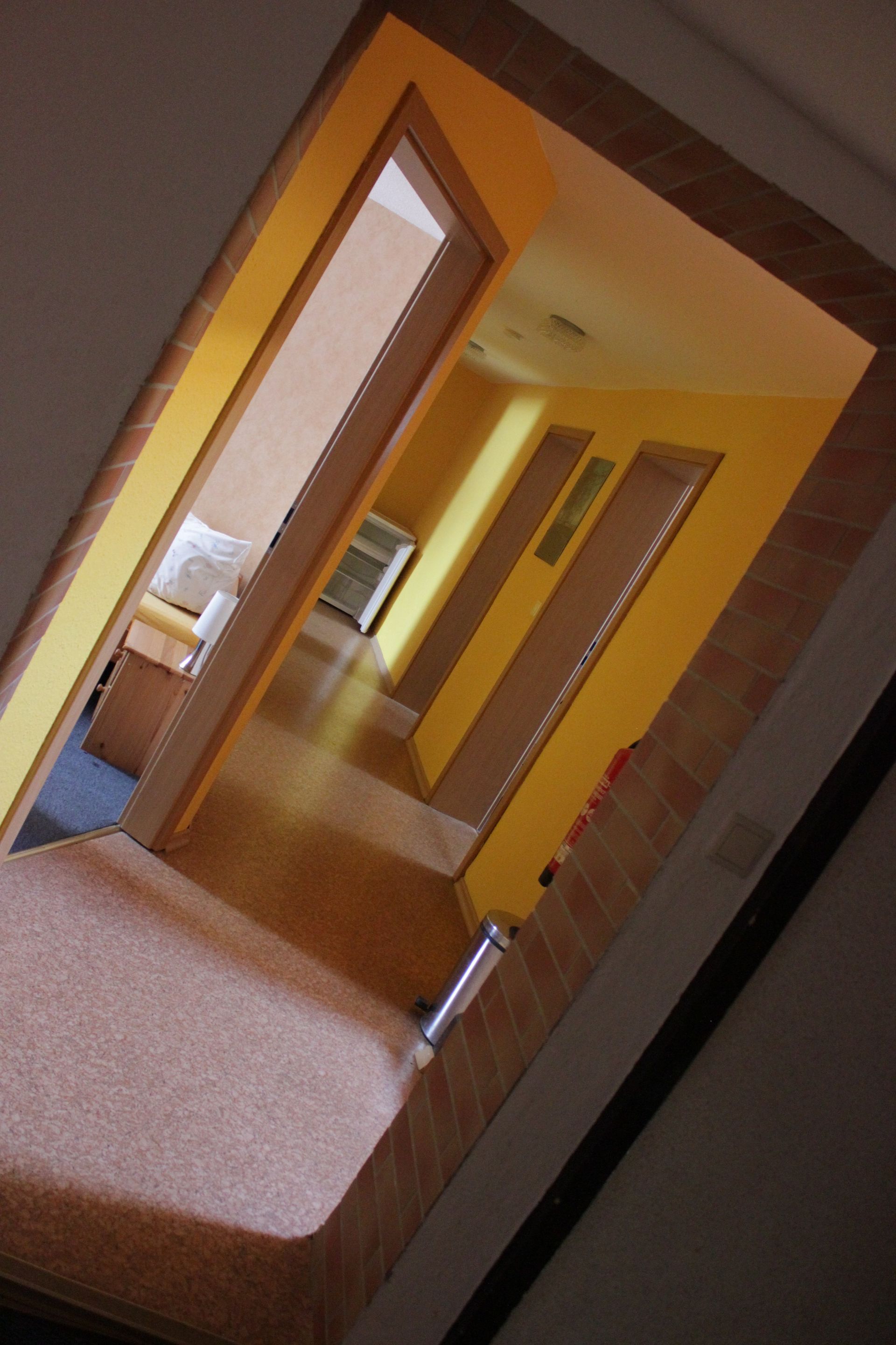 Ein Flur, der zu einem Schlafzimmer mit gelben Wänden führt