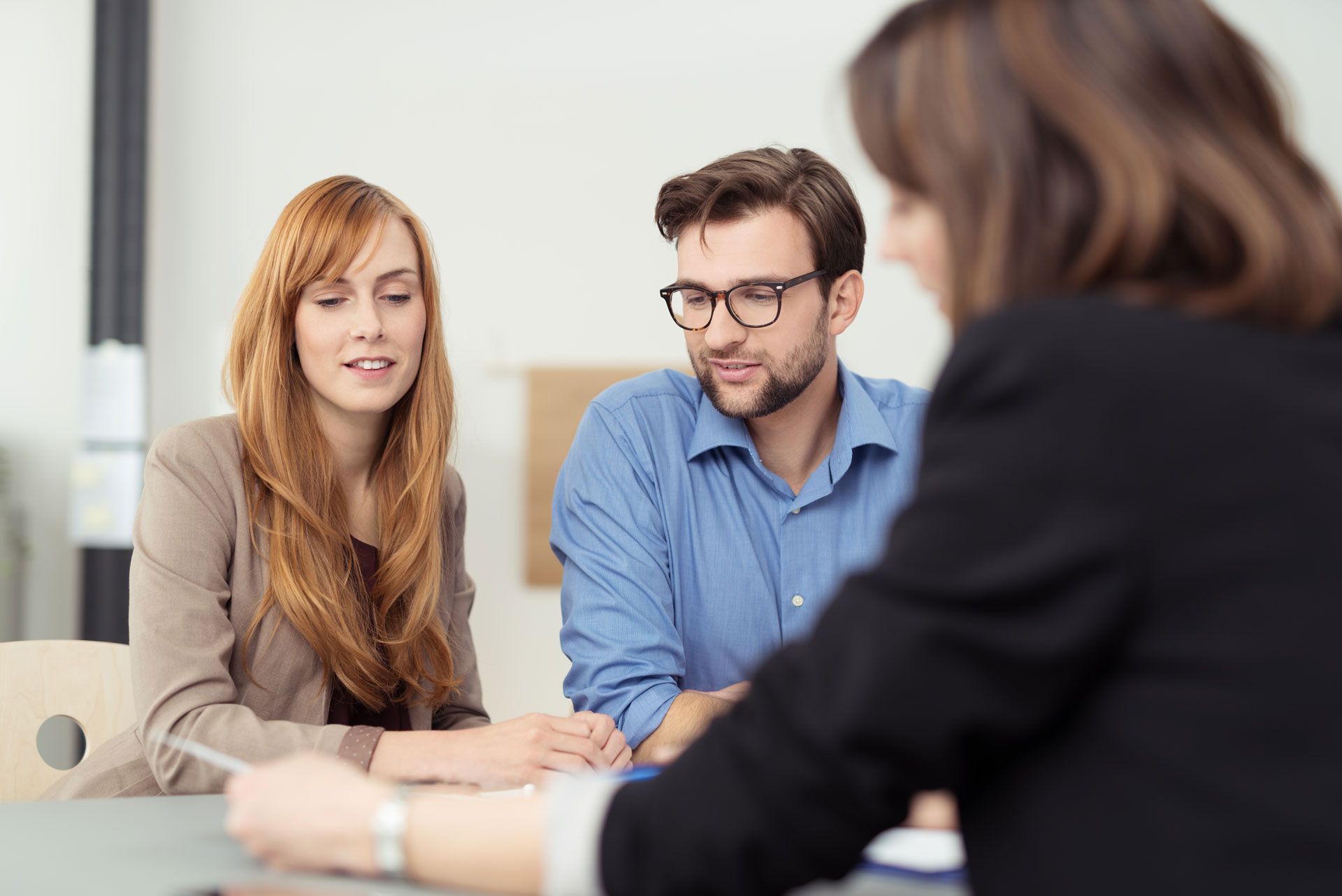 Couple reviewing documents with a professional in an office setting.