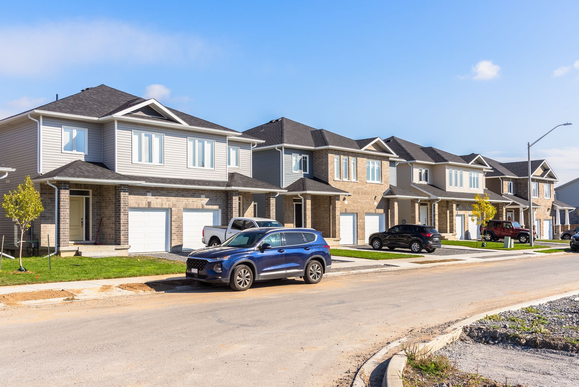 A blue suv is parked in front of a row of houses.