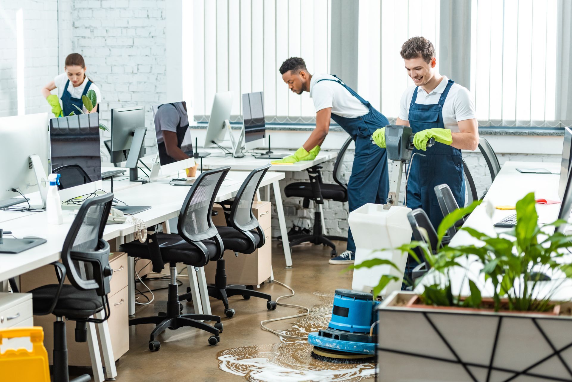 Two men are cleaning an office with a vacuum cleaner.