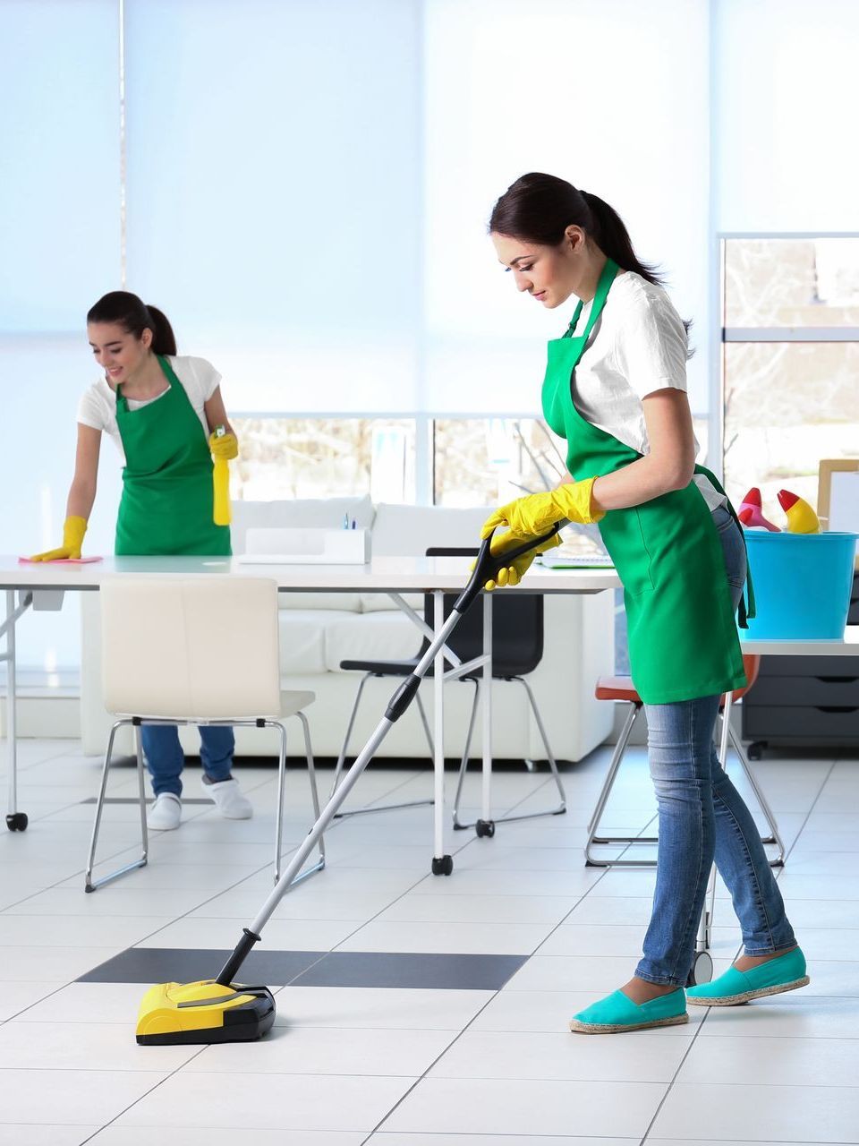 Two women are cleaning the floor in an office.