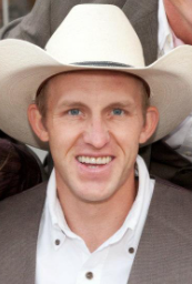 A man wearing a cowboy hat is smiling for the camera