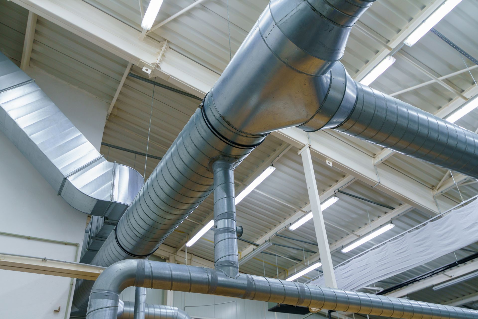 A bunch of pipes are hanging from the ceiling of a building.