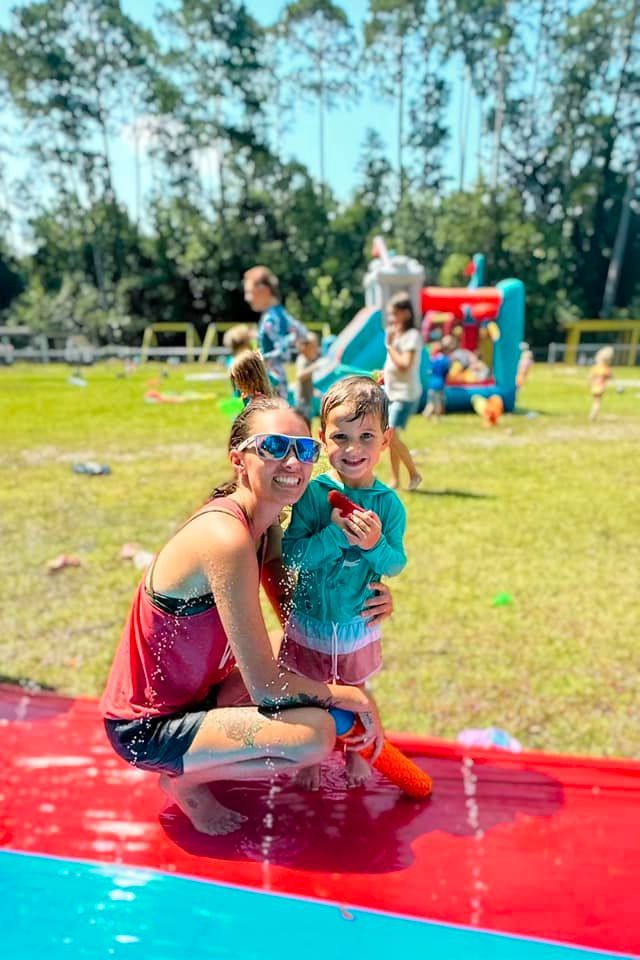 day care kid with woman on water slide