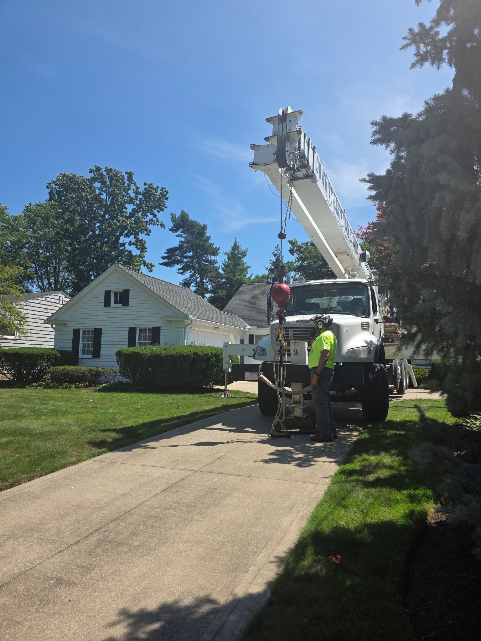 A tree service worker in a bucket lift cuts a tall tree.