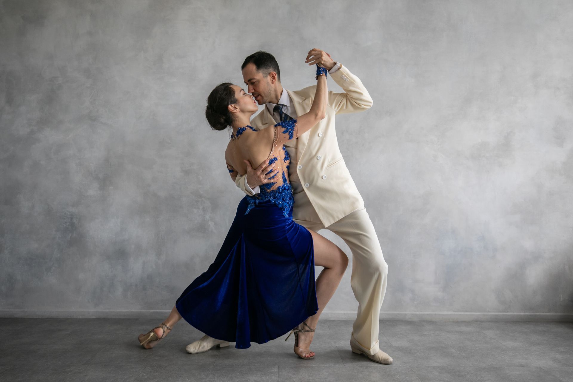 A man and woman dance the tango in a studio. 