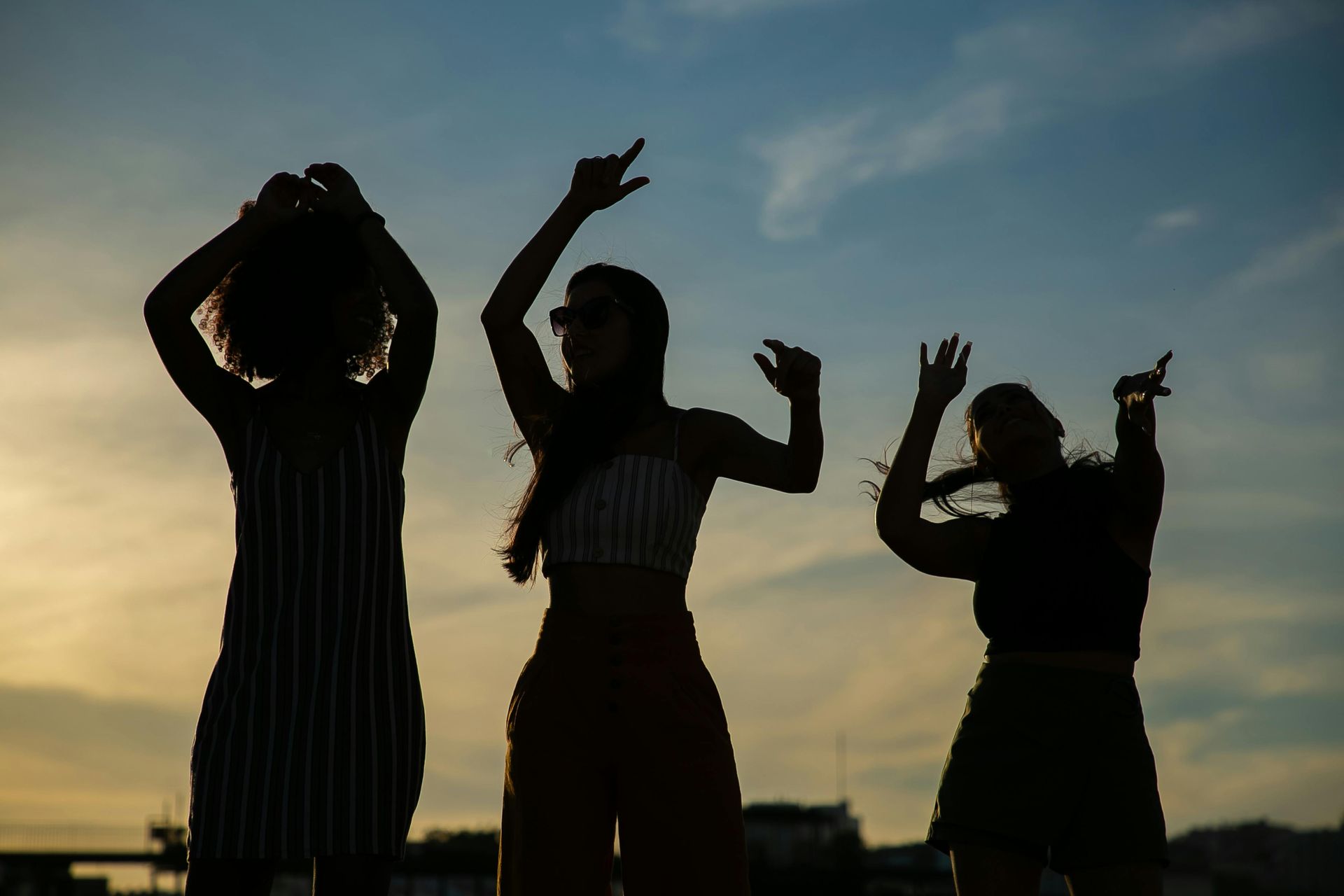 Silhouette of women dancing at sunset during an outdoor social dance party